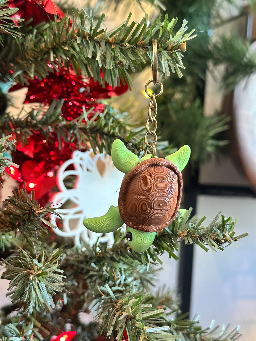 Green turtle keychain on a Christmas tree with red decorations