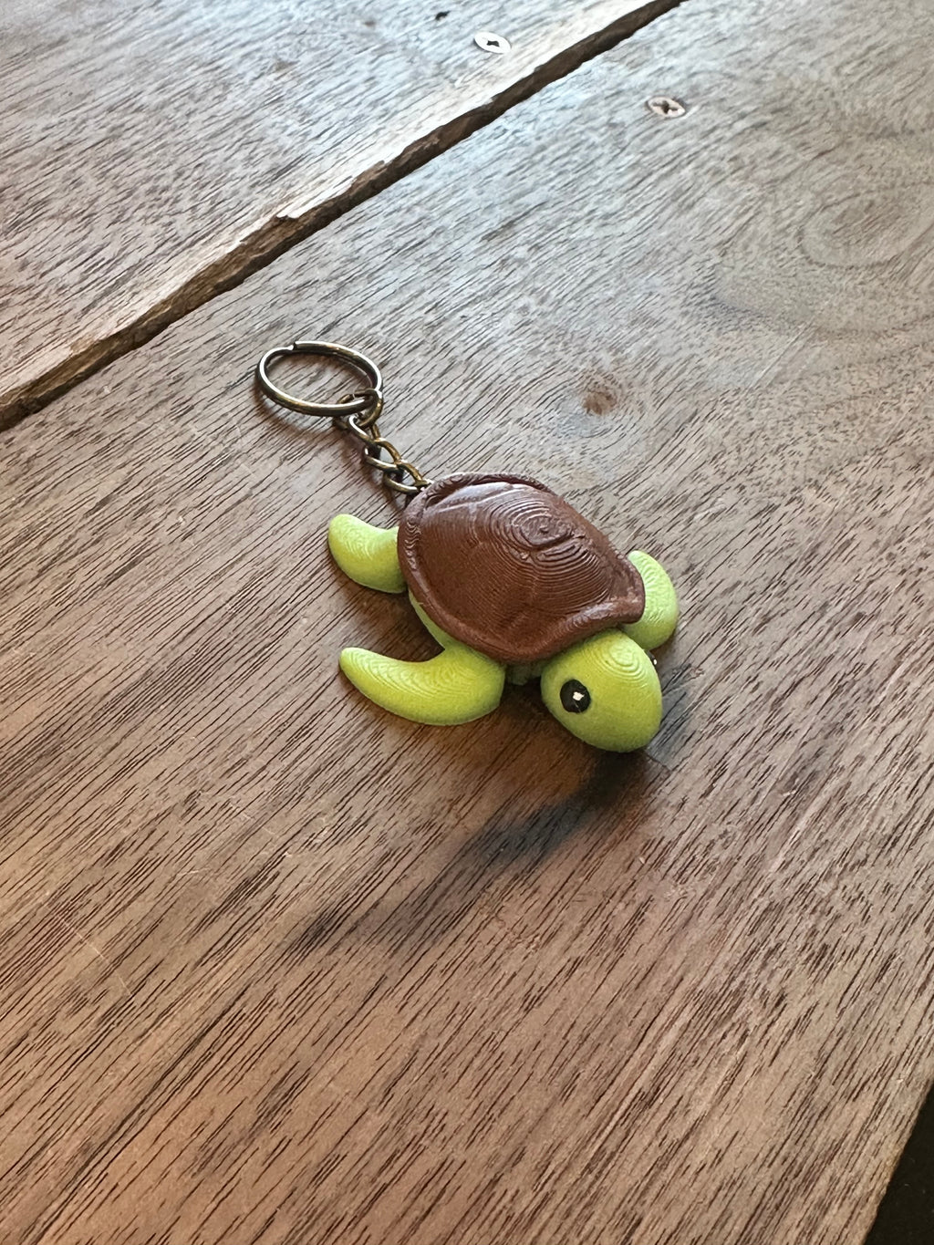 Green turtle keychain with brown shell on a wooden surface