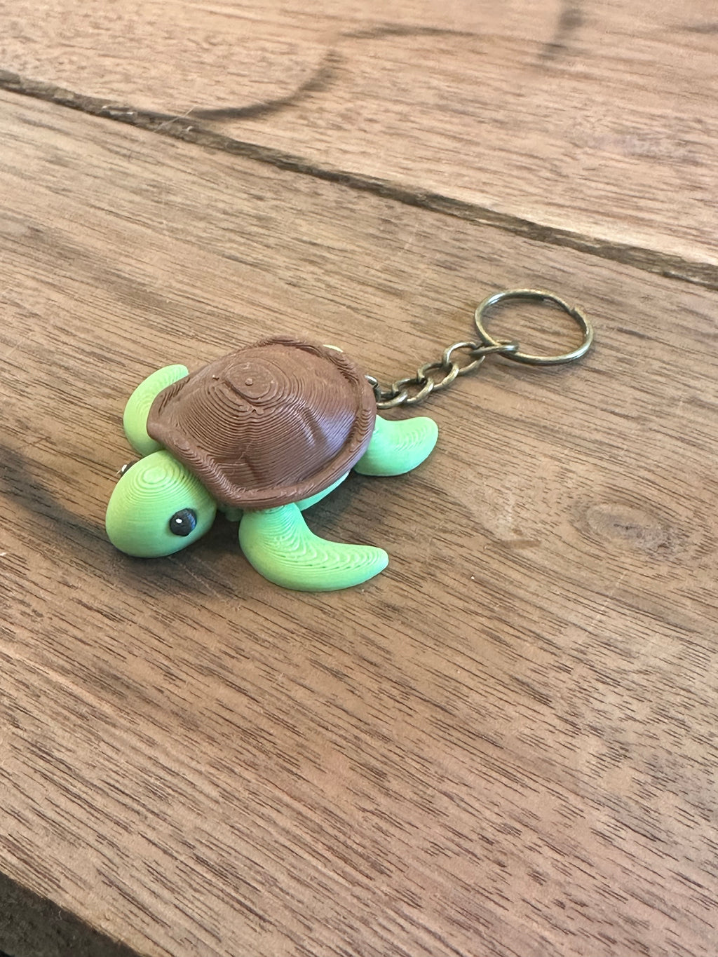 Green turtle keychain with brown shell on a wooden surface
