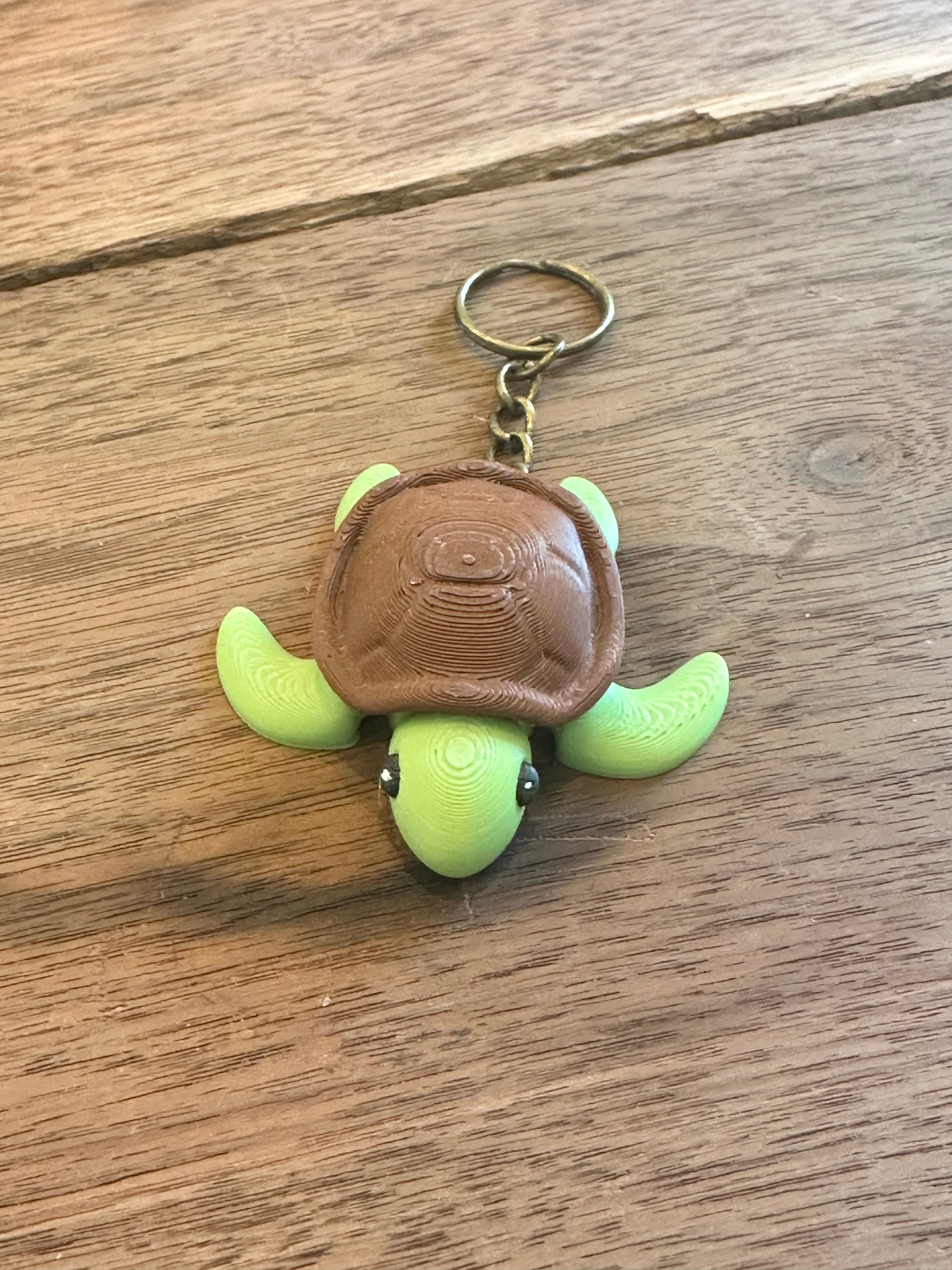 Turtle-shaped keychain with a brown patch on a wooden surface